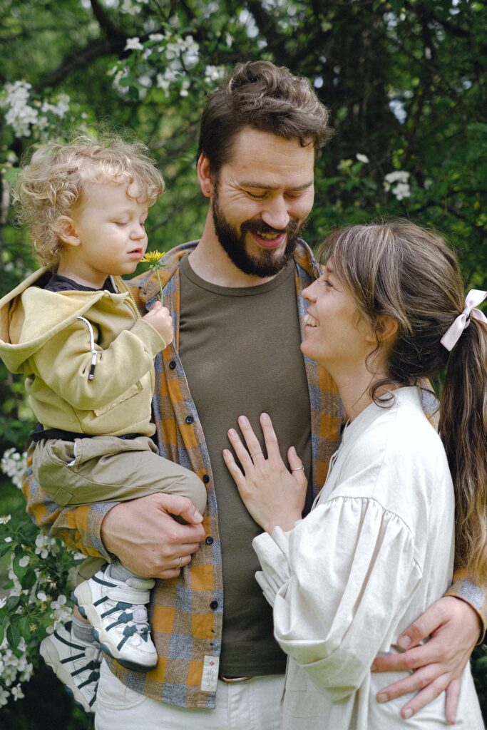 A smiling man and woman lovingly holding a child, gazing at each other, conveying a sense of family warmth and happiness